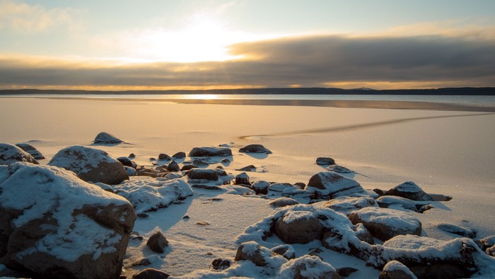 Frozen Lake Shore with Rocks at Sunset