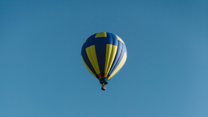 Blue and yellow hot air balloon in clear sky