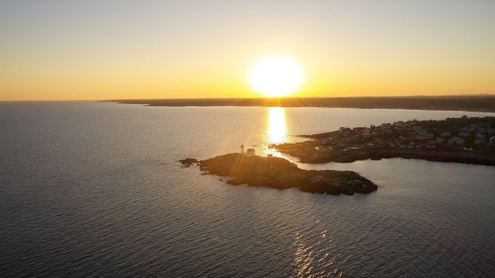 Sunset over a coastal town with a lighthouse