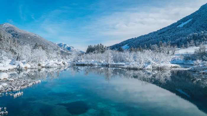 Snowy mountains and trees reflected in a clear blue lake