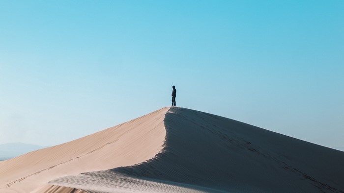 Person standing on a sand dune under a clear blue sky