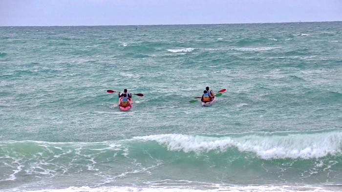 Two kayaks with people paddling in the ocean