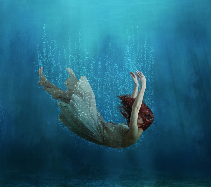 Woman falling underwater with bubbles