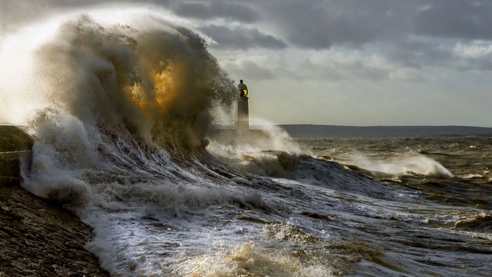 Massive wave crashing near a lighthouse