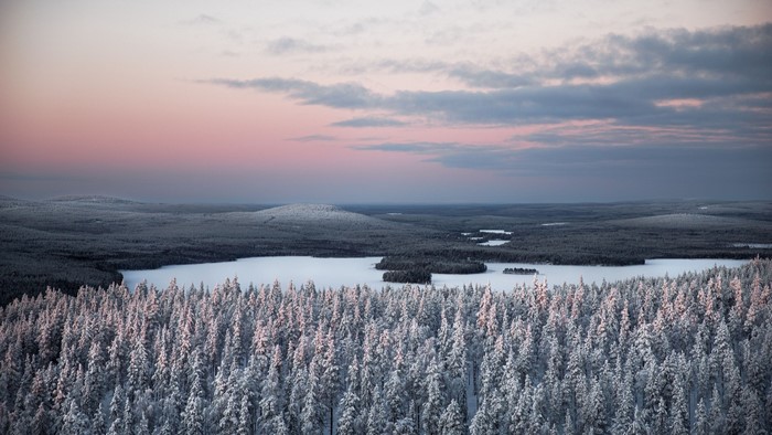 Snow-covered forest and frozen lake at sunset