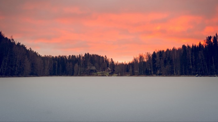 Frozen lake with forest and sunset sky