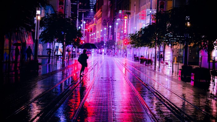 Person with umbrella on wet street at night