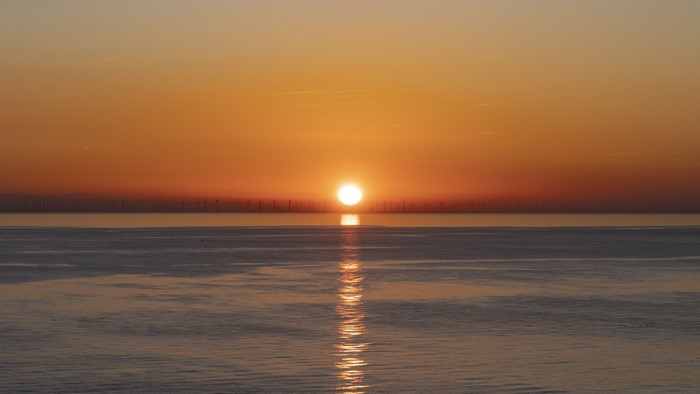 Sunset over the ocean with wind turbines