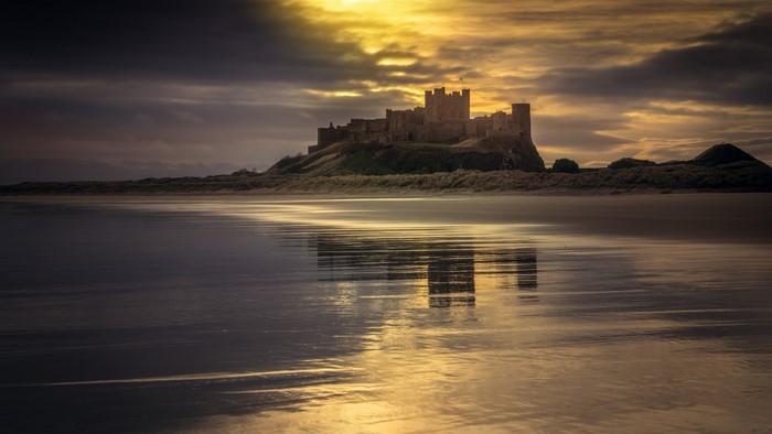 Bamburgh Castle reflection on beach at sunset