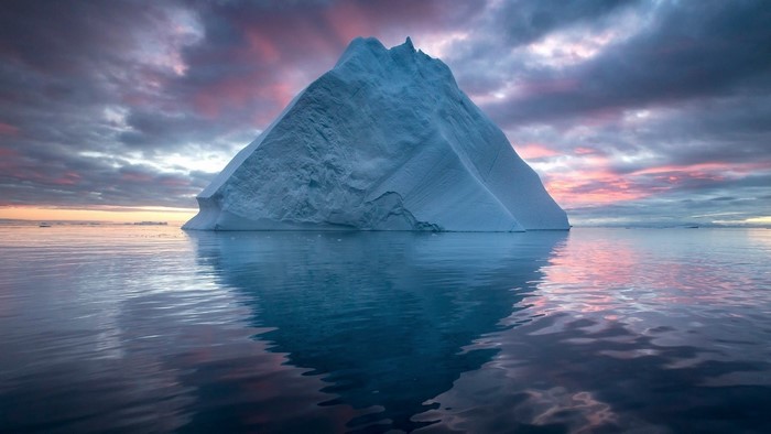 Iceberg in the ocean at sunset