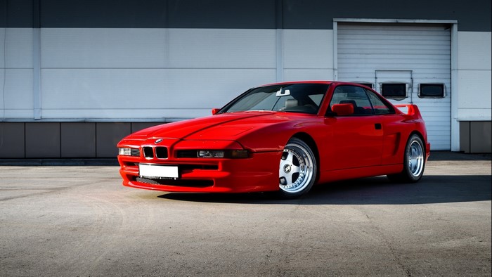 Red BMW E31 parked in front of a building