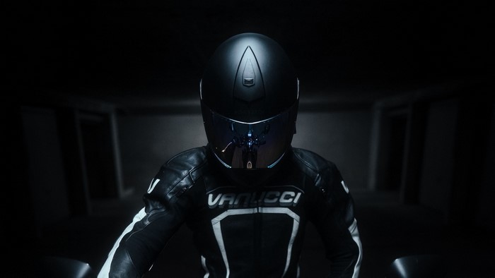 Motorcyclist wearing a black Vanucci racing suit and helmet