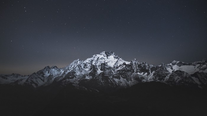 Snow-covered mountains under a starry night sky