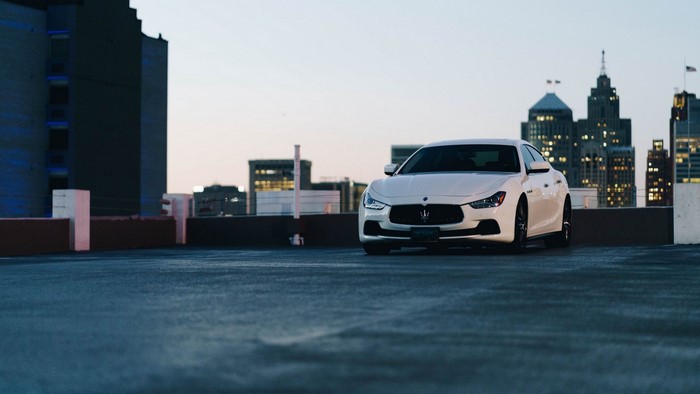 White Maserati Ghibli on a rooftop with city skyline