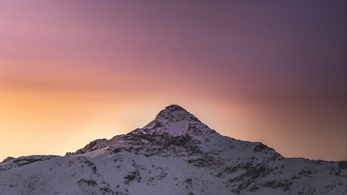 Snowy mountain peak at sunset