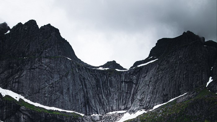 Dark, jagged mountains with snow patches under a cloudy sky