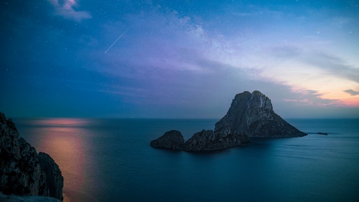Rock formation in the sea under starry sky