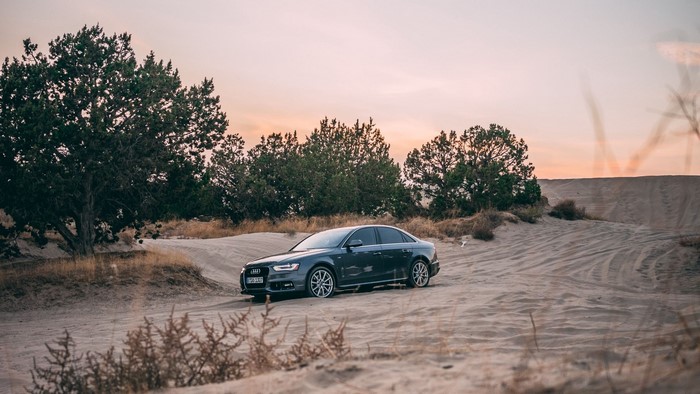 Dark gray Audi sedan on a sandy road