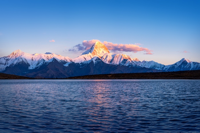 Snow-capped mountains reflected in a lake at sunset