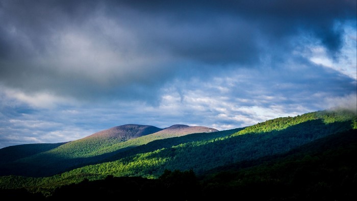 Sunlight on Rolling Hills Under Cloudy Sky