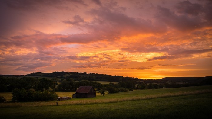 Sunset over rolling hills with a barn