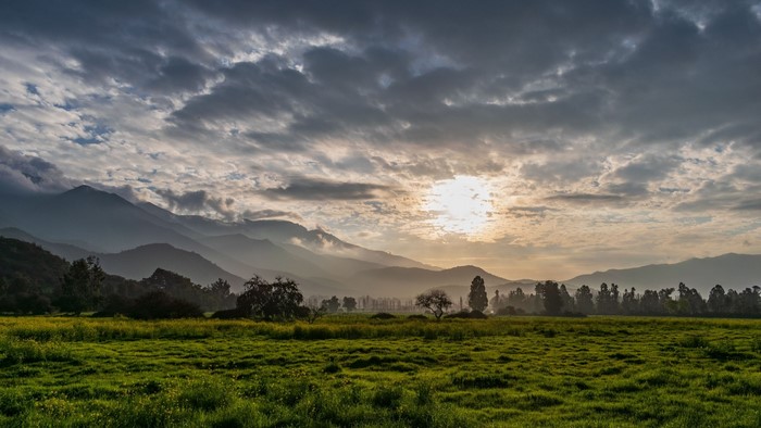 Sunlight over misty mountains and green field
