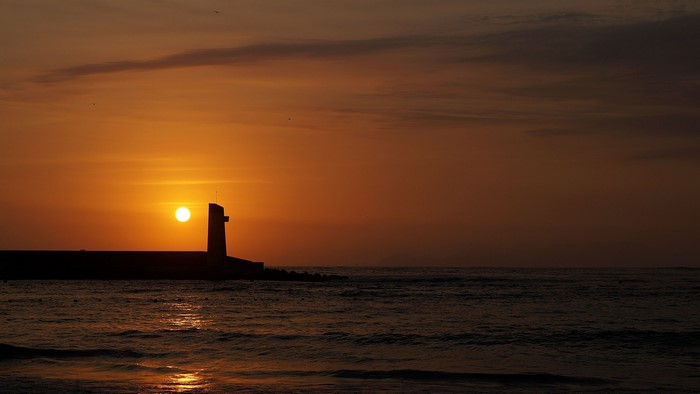 Lighthouse at sunset over the ocean