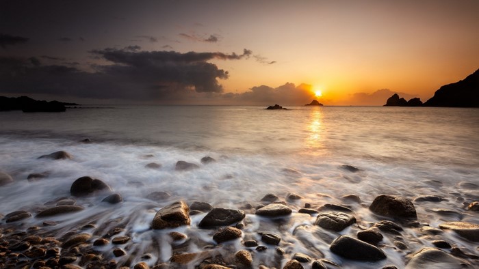 Sunset over a rocky beach with waves