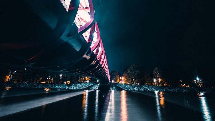 Bridge illuminated with pink lights over water at night