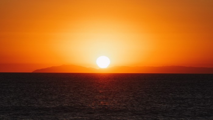Sunset over the ocean with distant islands