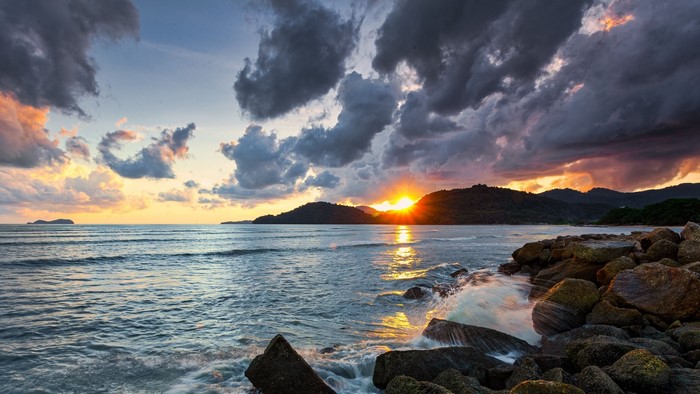 Sunset over the ocean with rocky shore