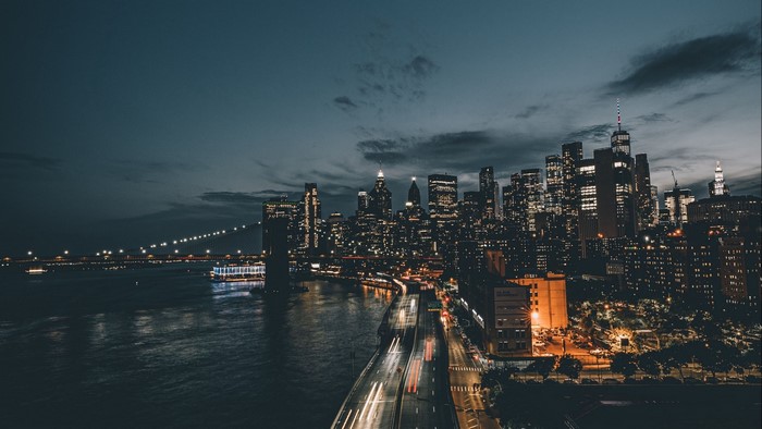 Nighttime cityscape with illuminated skyscrapers and bridge