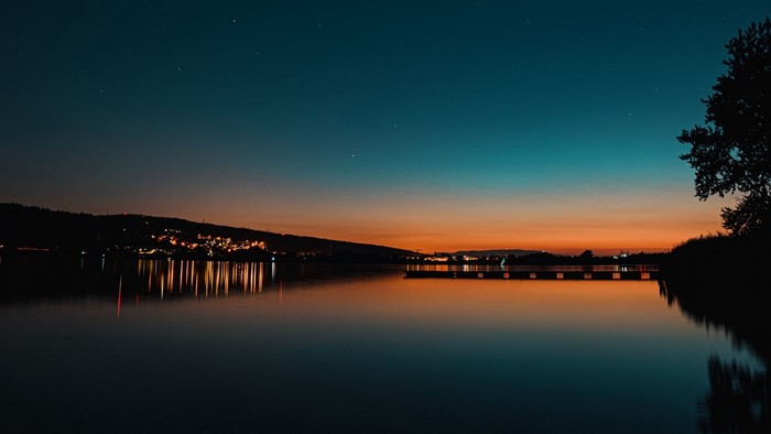 Night lake with city lights and stars