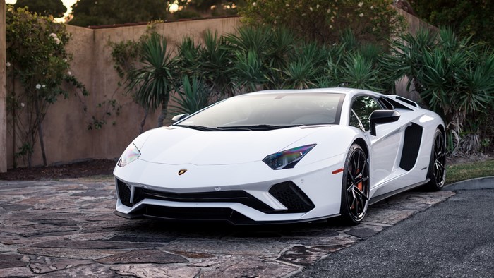 White Lamborghini Aventador parked on stone driveway