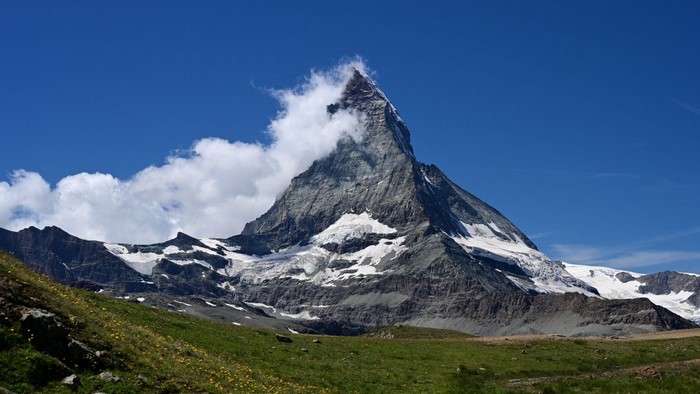 Matterhorn mountain with clouds and green meadow