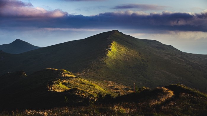 Mountain ridge illuminated by sunlight under dramatic clouds