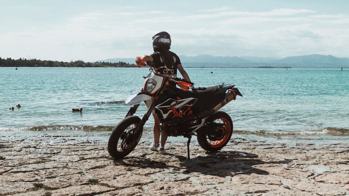 Person with KTM motorcycle on a rocky shore