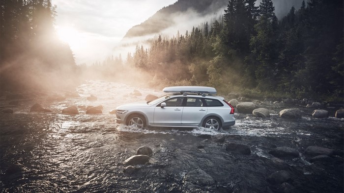 Volvo car driving through a river in a forest