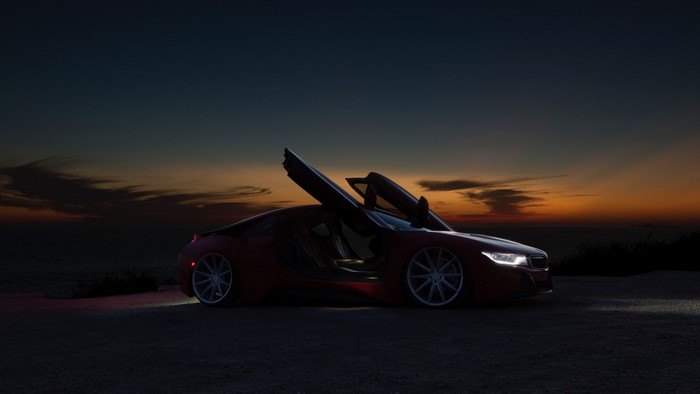 Red BMW i8 with doors open at sunset
