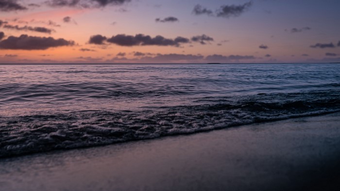 Ocean waves at sunset with clouds