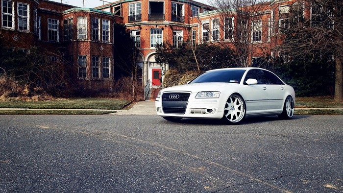 White Audi A8 parked in front of an abandoned building