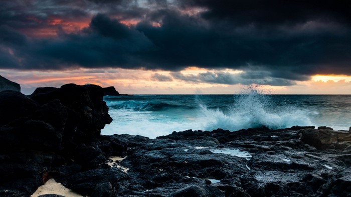 Waves crashing on rocky shore at sunset