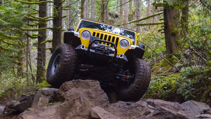 Yellow Jeep Wrangler off-roading on rocks