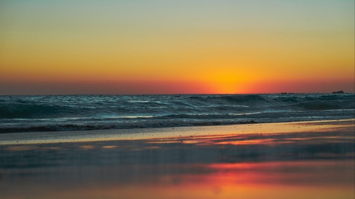 Sunset over the ocean with waves on the beach