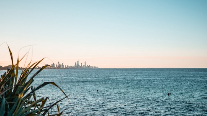 City skyline across the ocean with surfers