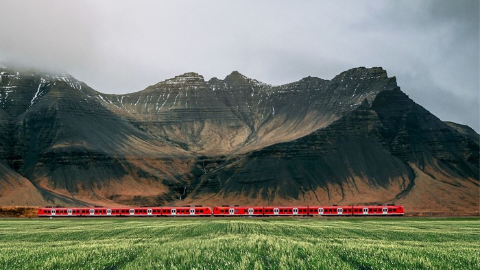 Red train in front of rocky mountains