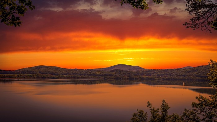 Sunset over a lake with hills and trees