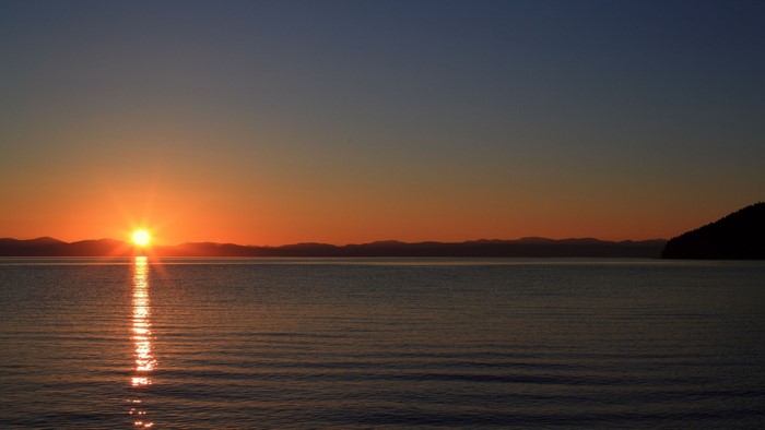 Sunset over a calm lake with distant mountains
