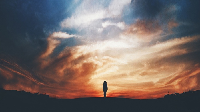 Silhouette of a girl against a dramatic sunset sky