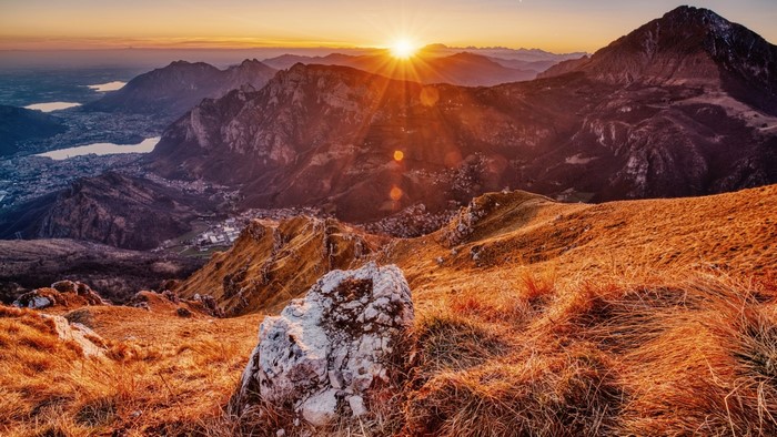 Mountain landscape at sunrise with sunburst over peaks